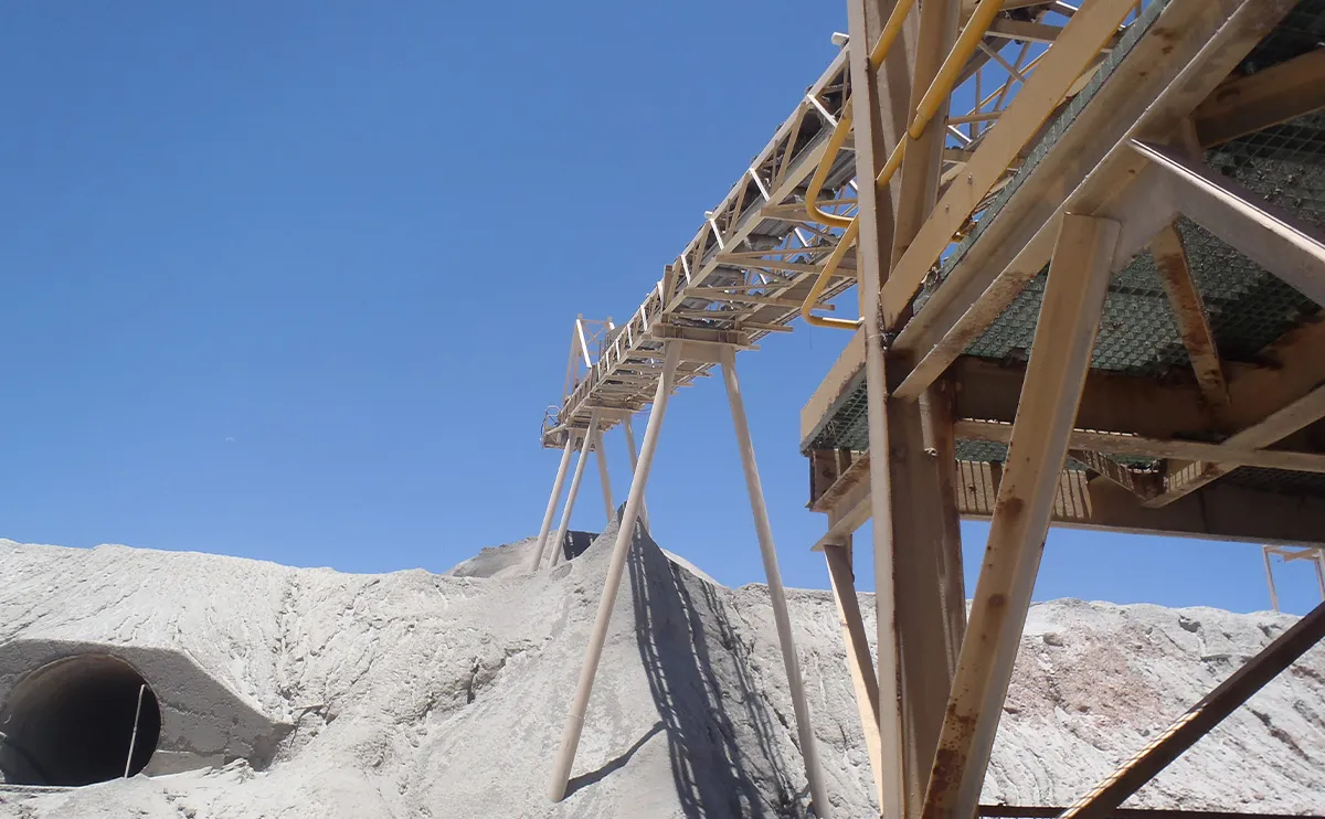 Elevated steel conveyor gantry stacker leading to a stockpile at a gold mine processing site